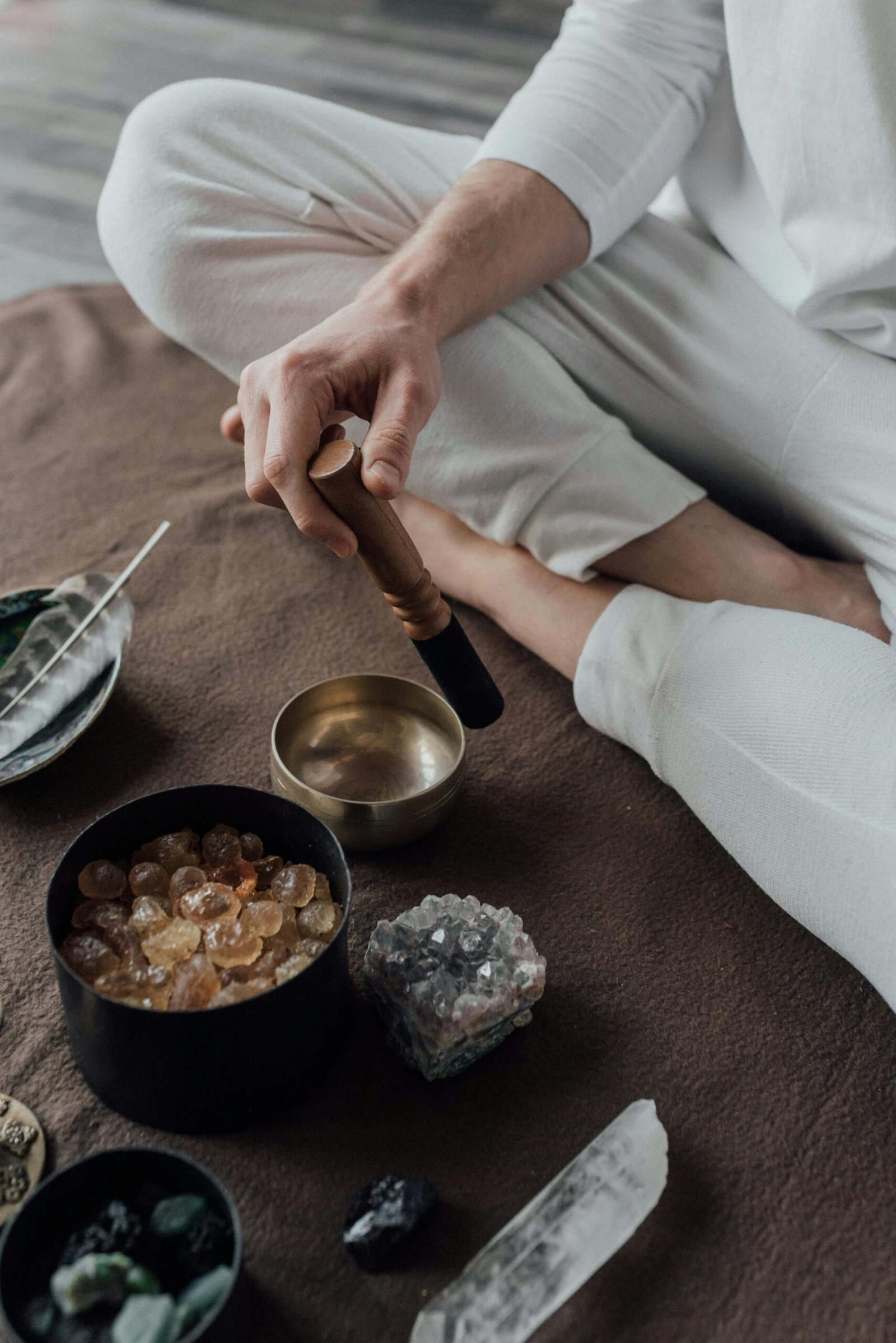 Man meditating with a singing bowl and healing crystals, capturing a serene spiritual practice.